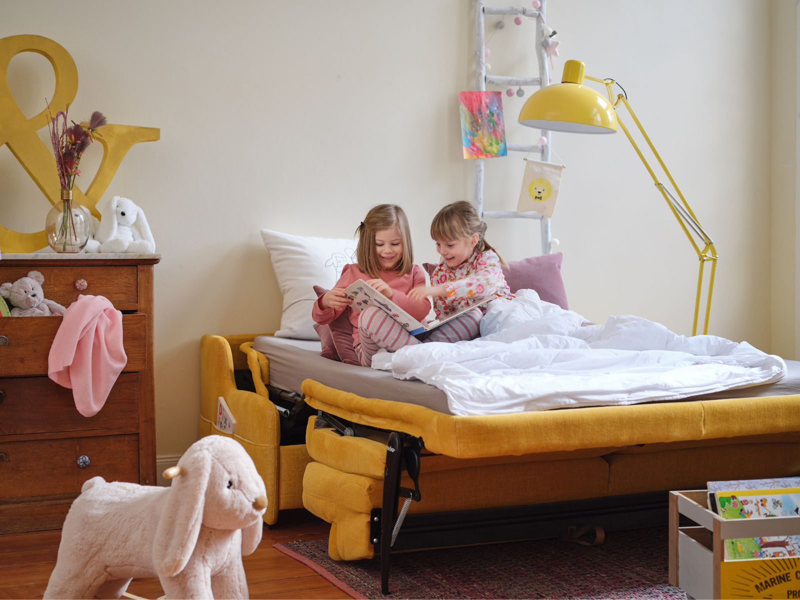 DORADO_2 Kinder auf einem gelben geöffneten Schlafsofa am lesen