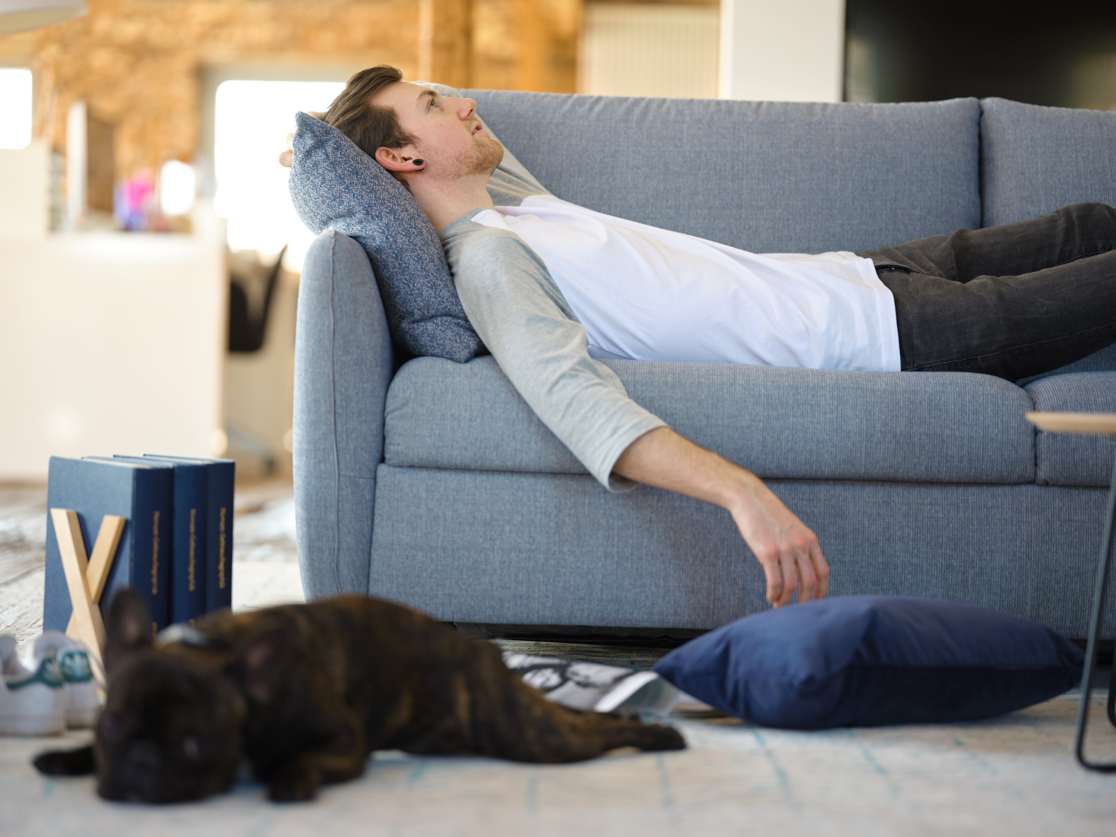 NOKTO_1 Junger Mann liegend auf einem blauen Schlafsofa